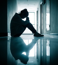 A sad woman sitting in a hallway in need of Grief Counseling in Peoria IL