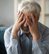 An unhappy man holding his head while struggling with a Chronic Mental Illness in Peoria IL